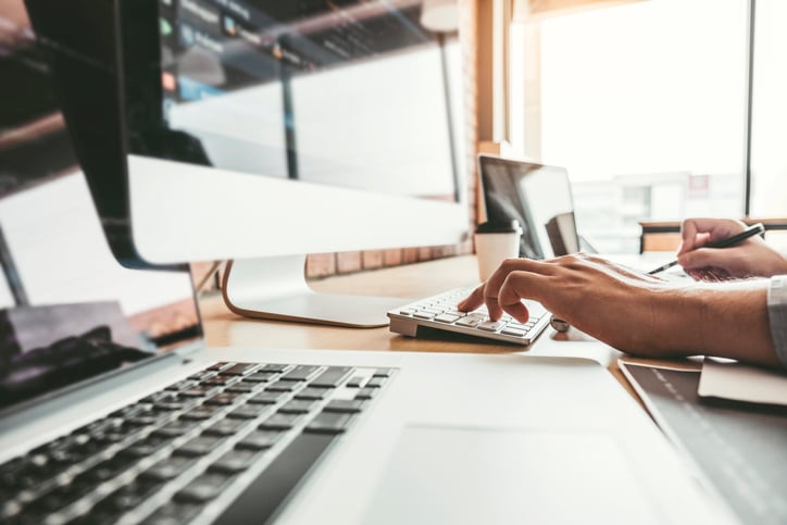 image shows someone typing on a laptop with a busy screen