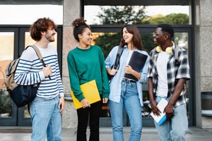 Image shows four students all looking at each other and laughing