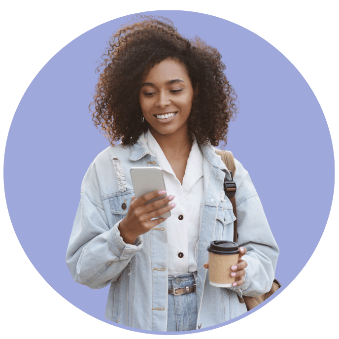 girl looking at mobile phone holding coffee cup