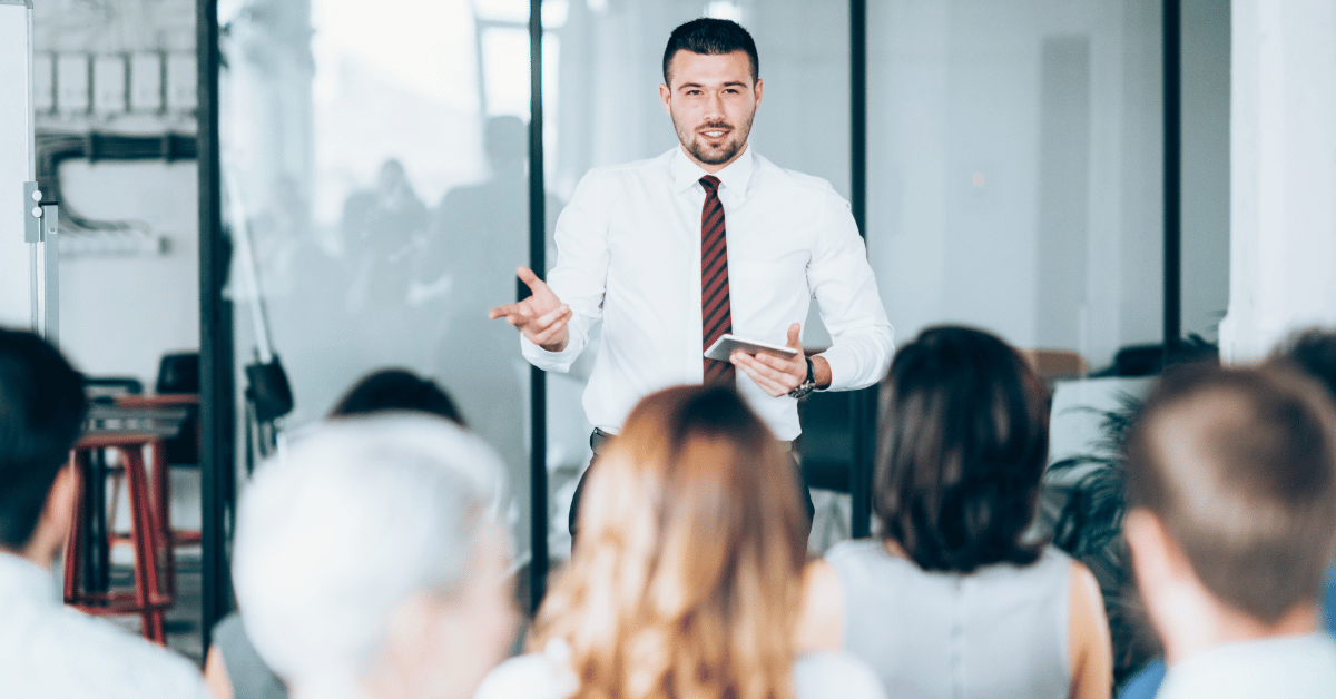 Male standing up delivering professional training to a group of employees.